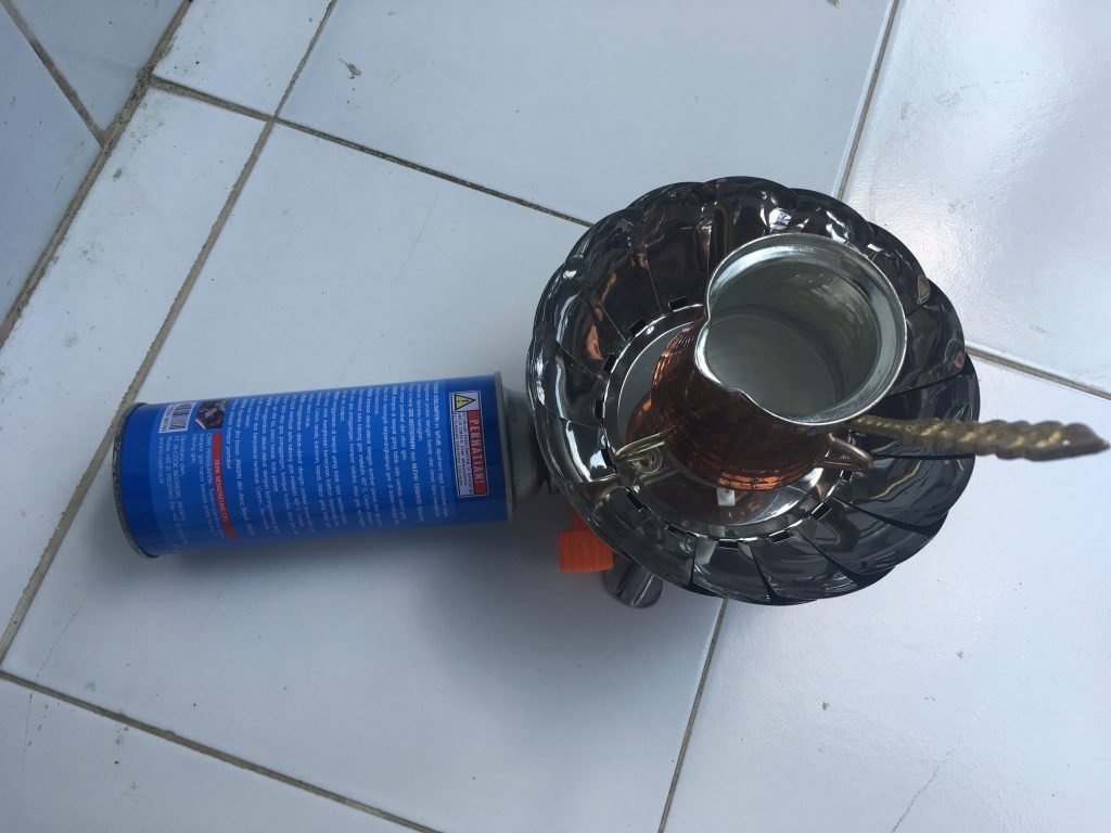 Agarose being melted on a camping stove with a traditional Turkish coffee pot with long handle used as a container for melting.